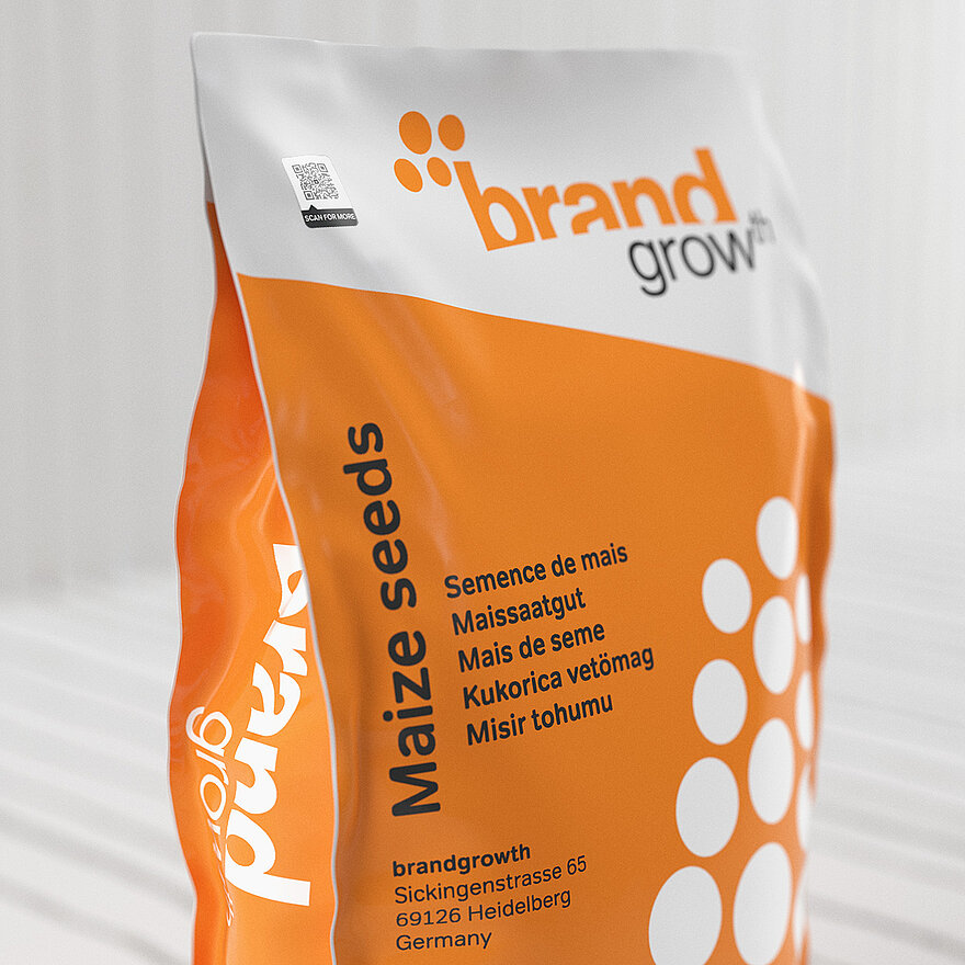 一袋橙色和白色的“Brand Grow”玉米种子。包装上贴有防伪码ValiGate®防伪标签，防伪标签上嵌入了带有安全图案的QR码。该标签可确保防伪，同时使用户能够使用智能手机验证产品并访问其他产品信息。